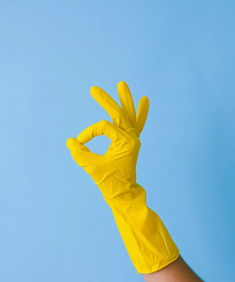 A hand in a yellow rubber glove making an OK sign, illustrating the rubber static method to remove dog hair from car